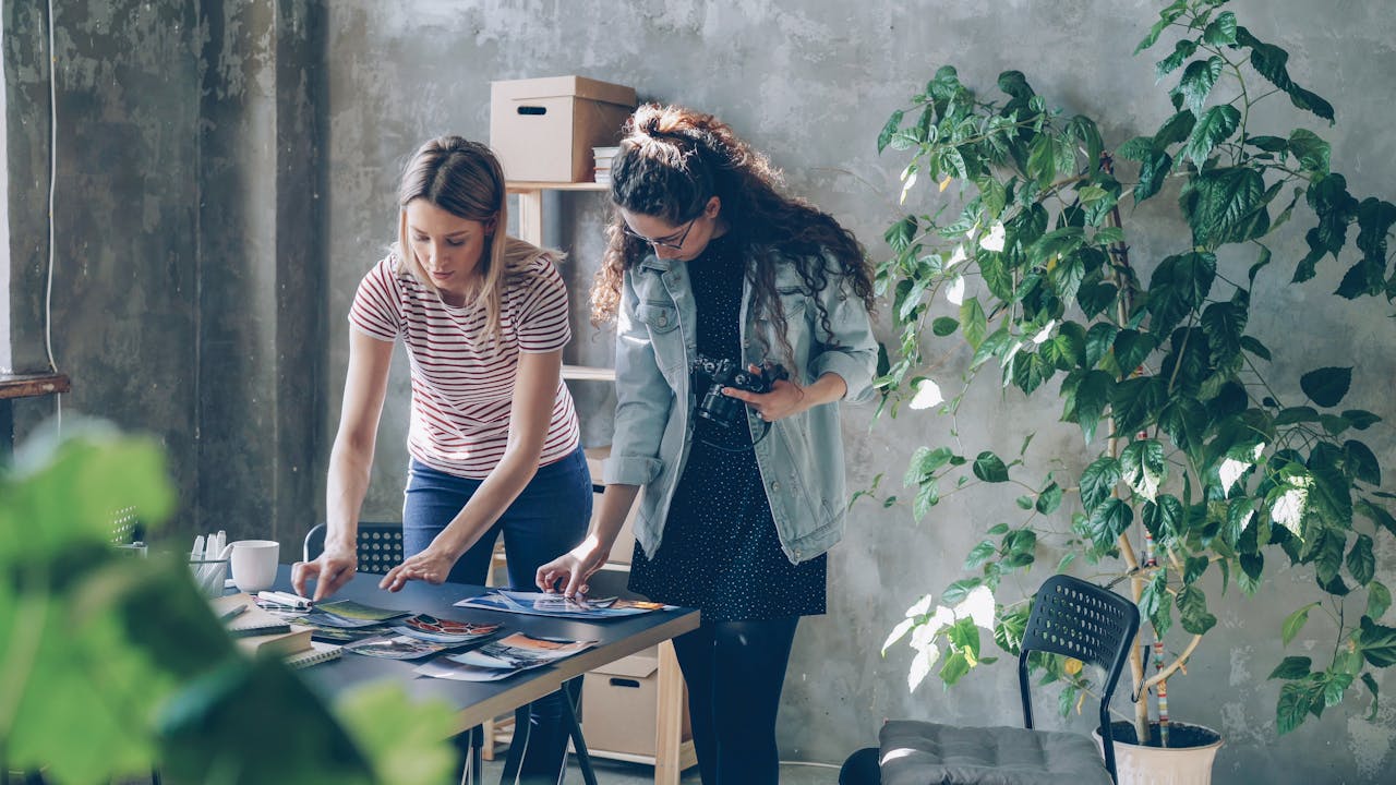 Two female designers examining photographs in a modern office space.